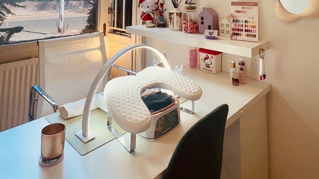 De nageltafel van de studio met een gebogen LED-lamp, handkussen, kleurkaart en planken met lakjes